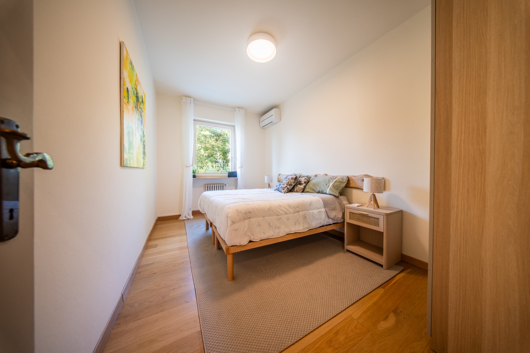 Peaceful double bedroom with yellow-toned artwork and garden window