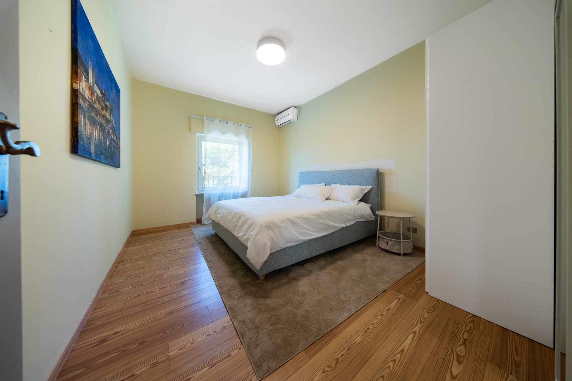 Soft green double bedroom with blue Venice artwork