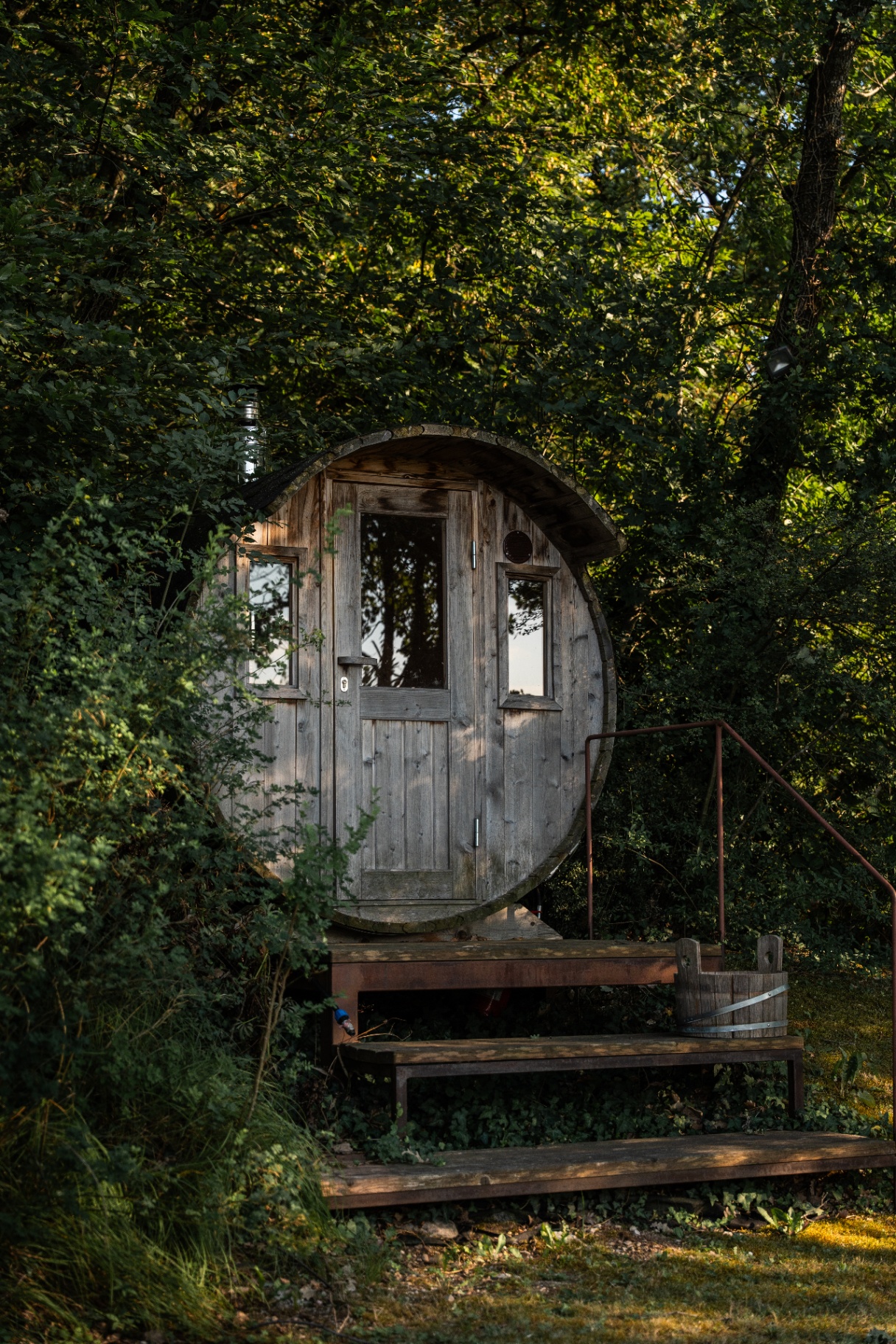 Barrel sauna at sunset, framed by woodland