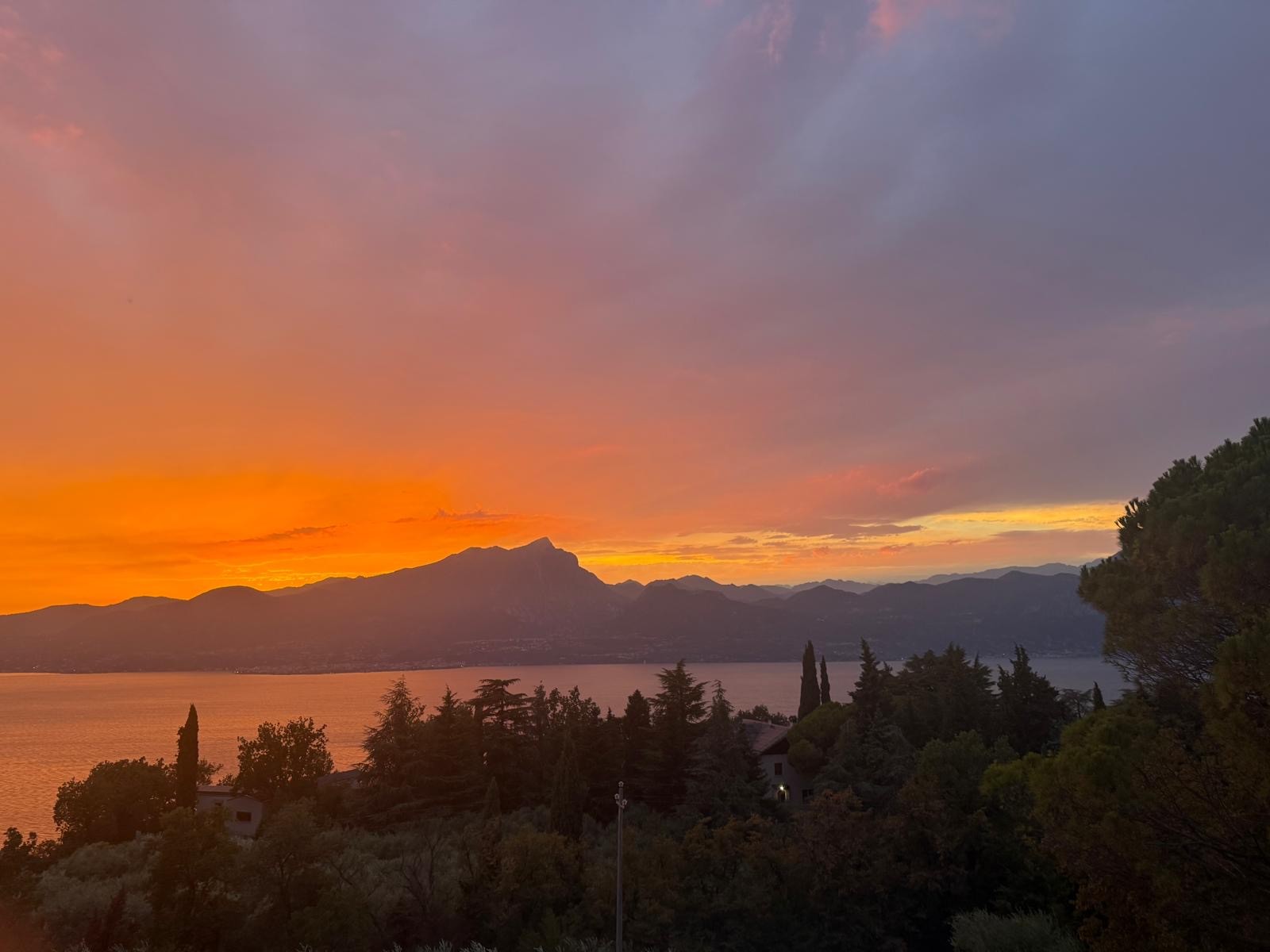 Fiery sunset behind Monte Luppio over Lake Garda